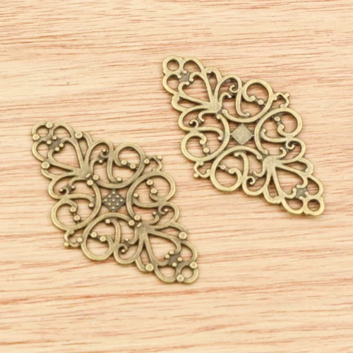 Face et revers de connecteurs allongés couleur bronze à volutes ajourées et losange central