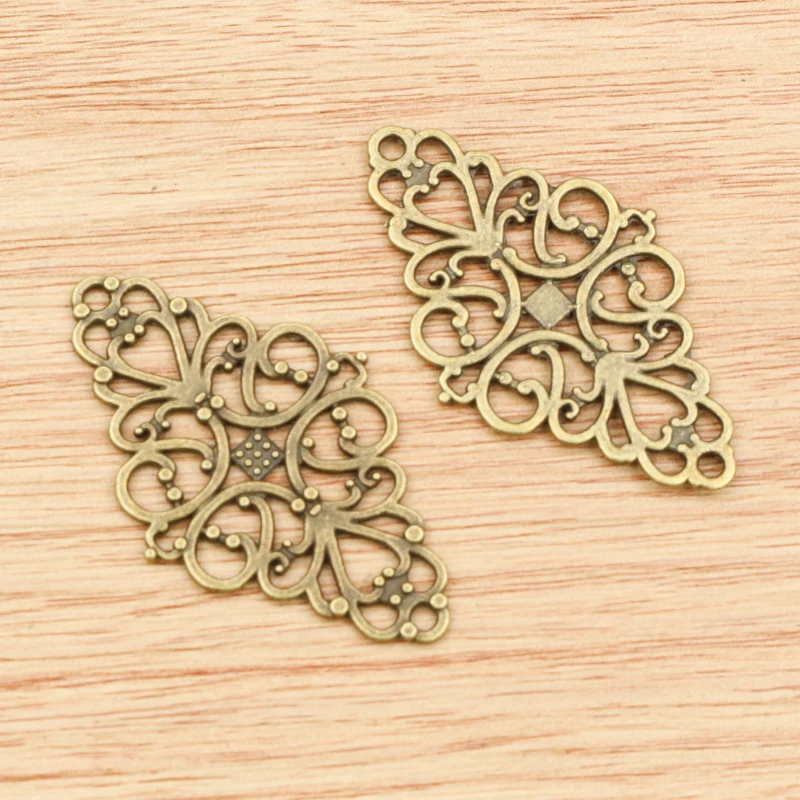 Face et revers de connecteurs allongés couleur bronze à volutes ajourées et losange central