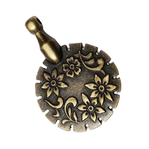 Un coupe-fil rond couleur bronze, décoré de fleurs et de volutes, avec des encoches sur le pourtour et un petit œillet